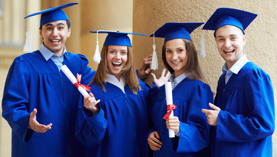 Group of smart students in graduation gowns looking at camera